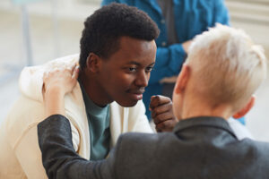 High angle view at young African-American man smiling gratefully to psychologist while while in support group circle, copy space